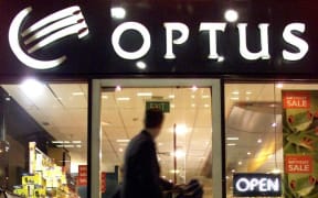 A rush-hour worker walks past an Optus telecommunications shop in downtown Sydney, 22 May 2001 after shares in Cable Wireless Optus Ltd fell again following the announcement by Singapore Telecommunications Ltd. (SingTel) of a high-risk takeover bid for the Australian telco.  The continuous drop of Optus shares is seen as a backlash against a recommendation by the company's independent directors recommending the 14 billion Australian dollar (7.1 billion US) offer to shareholders.  AFP PHOTO/WILLIAM WEST (Photo by WILLIAM WEST / AFP)