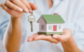 A woman holds keys to a new home.