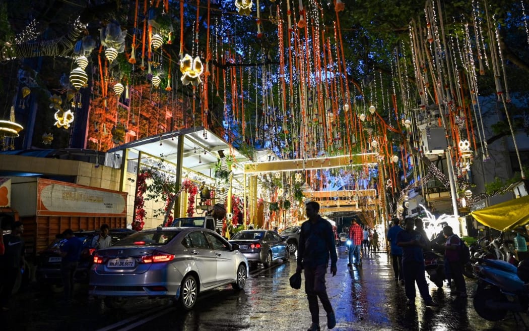 People walk past the Antilia mansion, house of billionaire Mukesh Ambani, while it is lit up ahead of his son Anant Ambani's wedding, in Mumbai.