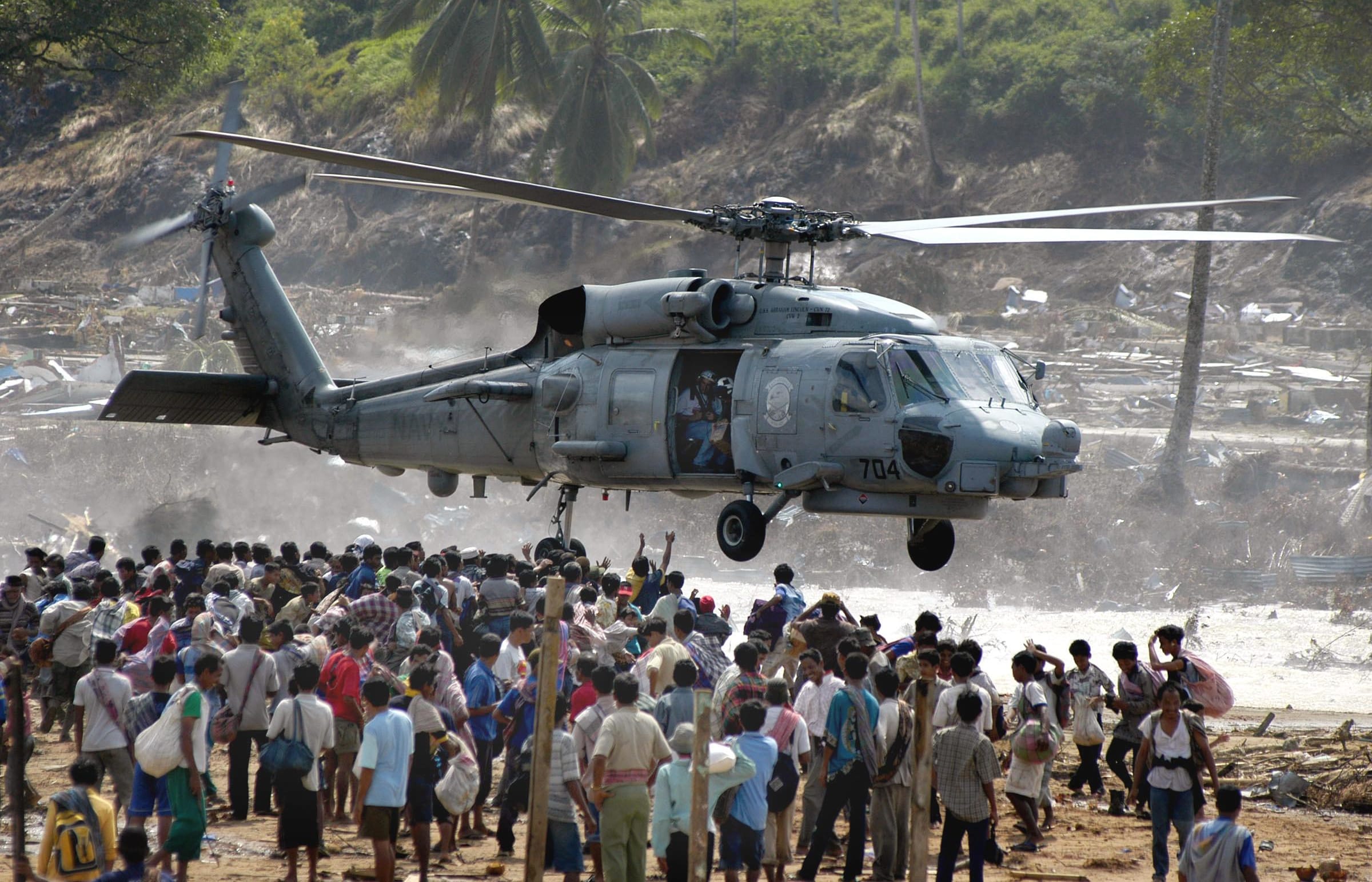 Hundreds of residents of Calang town flock under a US helicopter as volunteers distribute food in Aceh Jaya, in the tsunami-ravaged western Aceh coast, 04 January 2005.