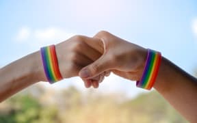 Rainbow wristbands in wrists of asian boy couple with blurred background, concept for celebration of lgbtq+ community in pride month or in June around the world.