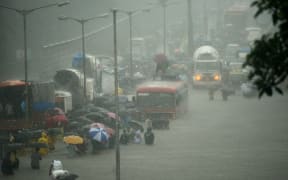 Mumbai residents wade through a flooded street during heavy rain showers on 29 August.