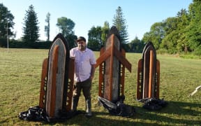 The artist Tamatamarangi Clausen with three pou created from parts of homes devastated by Cyclone Gabrielle.