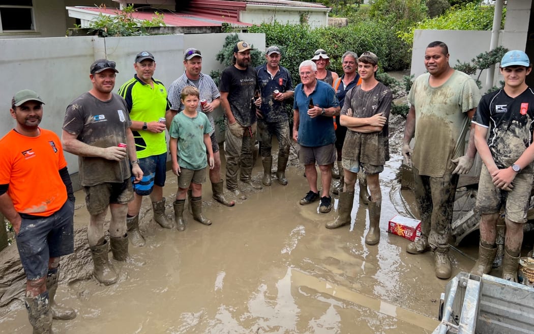 Builders and other volunteers surround Bill Moore (centre) following Cyclone Gabrielle.