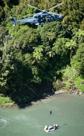 An NH90 Air Force helicopter winches a car from the Mohaka River.