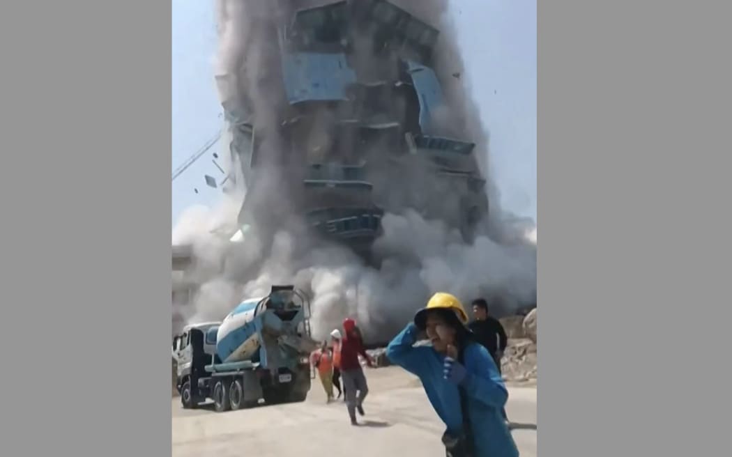 This frame grab from UGC video footage taken and posted by Khon Su Cheevit Adeet Mai Suay Rok Na on Facebook on March 28, 2025 shows workers running away from a building as it collapses at a construction site in Bangkok