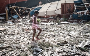 A girl collects artificial flowers from the rubble of a building destroyed by the cyclone Idai at Sacred Heart Catholic Church in Beira, Mozambique.