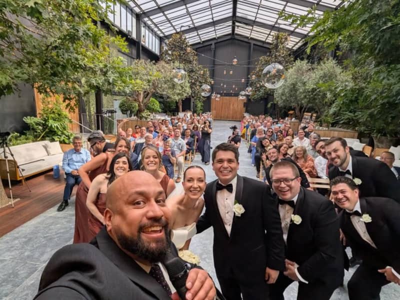 Auckland celebrant Nate Dunn takes a selfie with a couple and their guests from the stage.