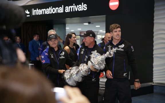 Team NZ crew members, from left, Glenn Ashby, Peter Dalton and Peter Burling, bringing the America's Cup trophy home.