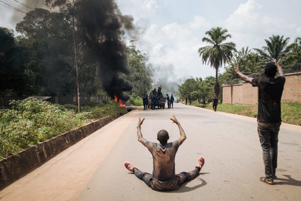 Protesters gesture in front of a police platoon near the electoral commission in Beni.