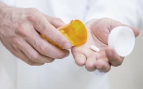 A man pours a pill into his hand.