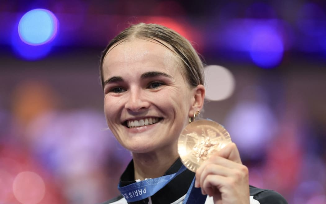 New Zealand's Ally Wollaston celebrates her bronze medal on the podium of the women's track cycling omnium event of the Paris 2024 Olympic Games at the Saint-Quentin-en-Yvelines National Velodrome in Montigny-le-Bretonneux, south-west of Paris, on August 11, 2024. (Photo by Emmanuel DUNAND / AFP)