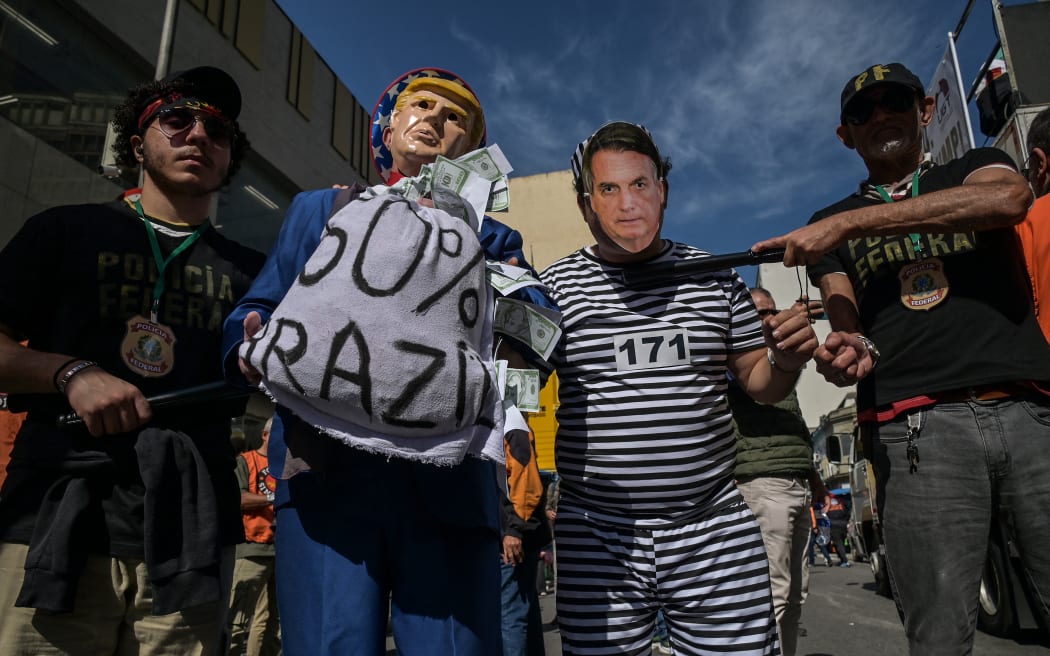 Protesters wearing masks depicting US President Donald Trump and former Brazilian President Jair Bolsonaro take part in a protest in defence of retail employment and national sovereignty at 25 de Marco, a popular shopping street in downtown Sao Paulo, Brazil, on July 18, 2025. Brazilian President Luiz Inacio Lula da Silva on July 17 slammed Donald Trump's threat to impose 50 percent tariffs on Latin America's largest economy as "unacceptable blackmail." (Photo by Nelson ALMEIDA / AFP)