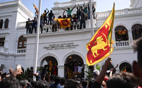 Demonstrators wave Sri Lankan flags during an anti-government protest in the office building of Sri Lanka's prime minister in Colombo on 13 July 2022.