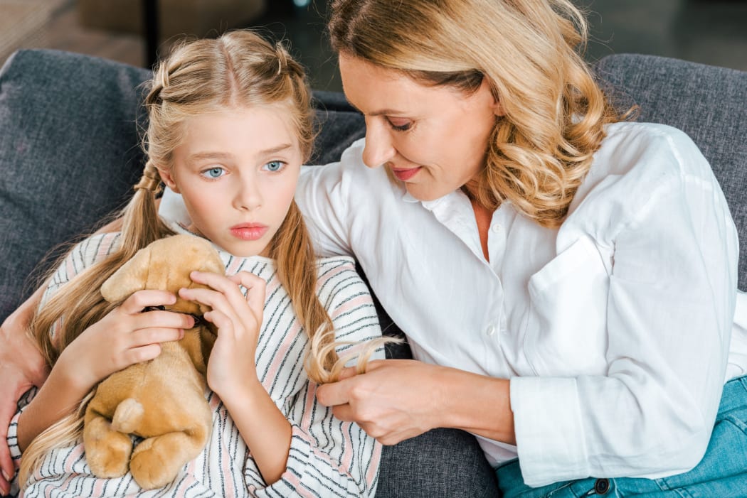 A photo of a young girl sitting with her mother on the couch. It looks like they've been having a serious conversation