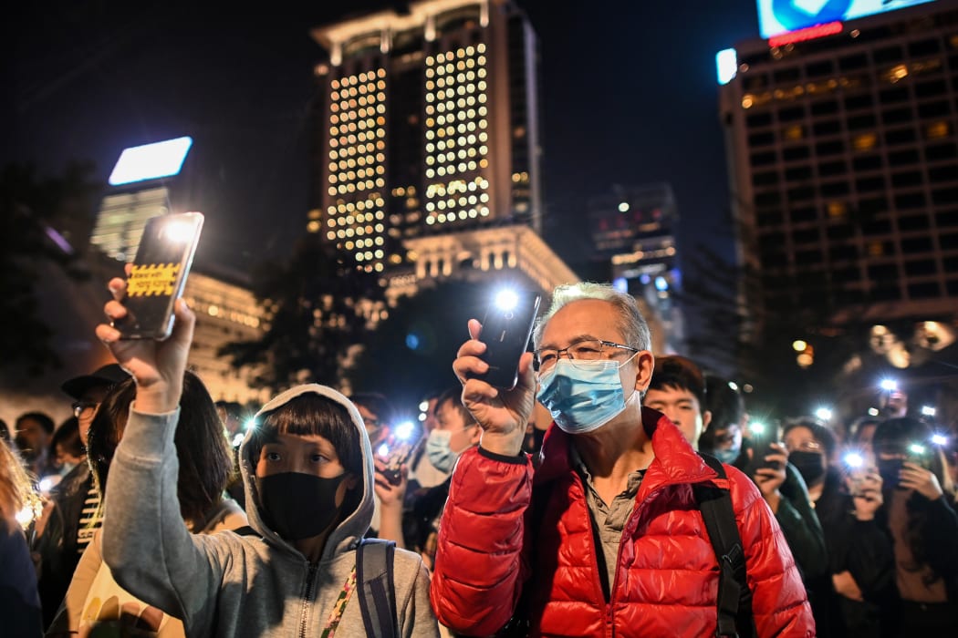 People hold their mobile phones as they gather to pray for the students who are barricaded inside Hong Kong Polytechnic University.