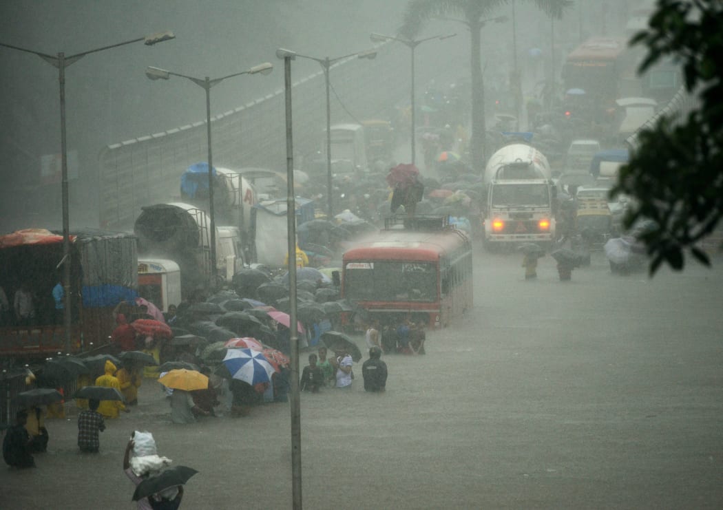 Mumbai residents wade through a flooded street during heavy rain showers on 29 August, 2017.