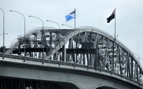 The New Zealand flag flies alongside its challenger on Auckland's Harbour Bridge.