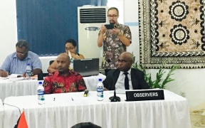An Indonesian captures the Melanesian Spearhead Group proceedings, 20 December 2016 in Port Vila, on device. West Papuan representatives Benny Wenda and Octo Mote (MSG observers with the United Liberation Movement) in foreground.