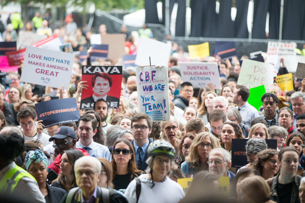 Activists hold signs at a rally calling on Sen. Jeff Flake (R-AZ) to reject Judge Brett Kavanaugh's nomination to the Supreme Court.