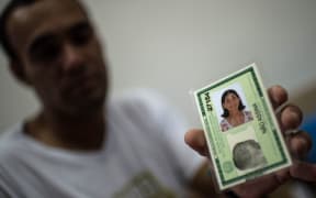 Marcello Jose Felicio, 30, shows the ID of his mother Maria "Gracita" who disapeared during the mudslide that buried their village, Bento Rodrigues, in Mariana, Brazil, on 8 november, 2015 AFP PHOTO / CHRISTOPHE SIMON