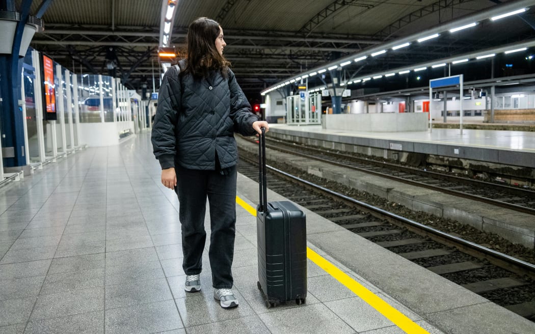 A woman with a wheely suitcase at a train station