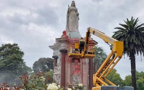 A council worker cleans the statue to Britain's Queen Victoria that was defaced in the Royal Botanic Gardens Victoria in Melbourne on January 25, 2024, ahead of Australia Day. (Photo by Martin PARRY / AFP)