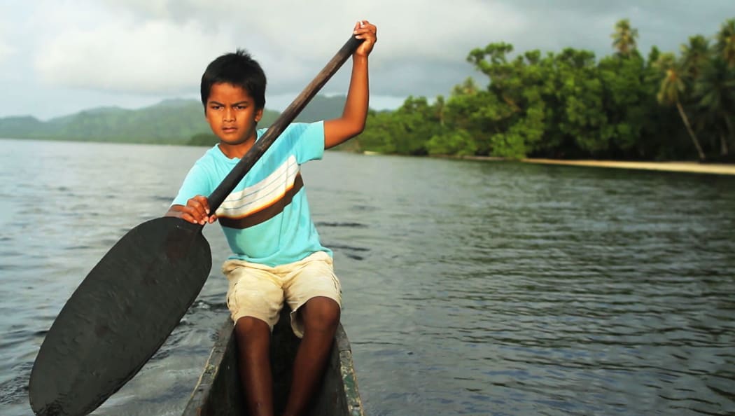 A young boy paddles in Kosrae, Federated States of Micronesia.