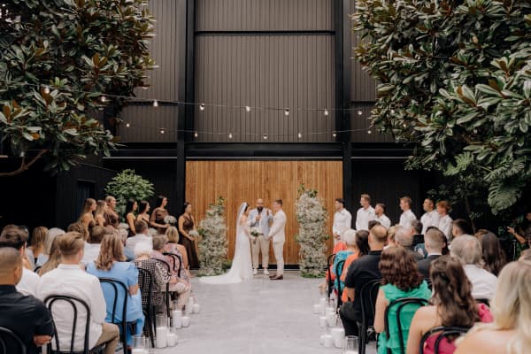 Auckland celebrant Nate Dunn in a wedding venue with guests and a couple getting married.