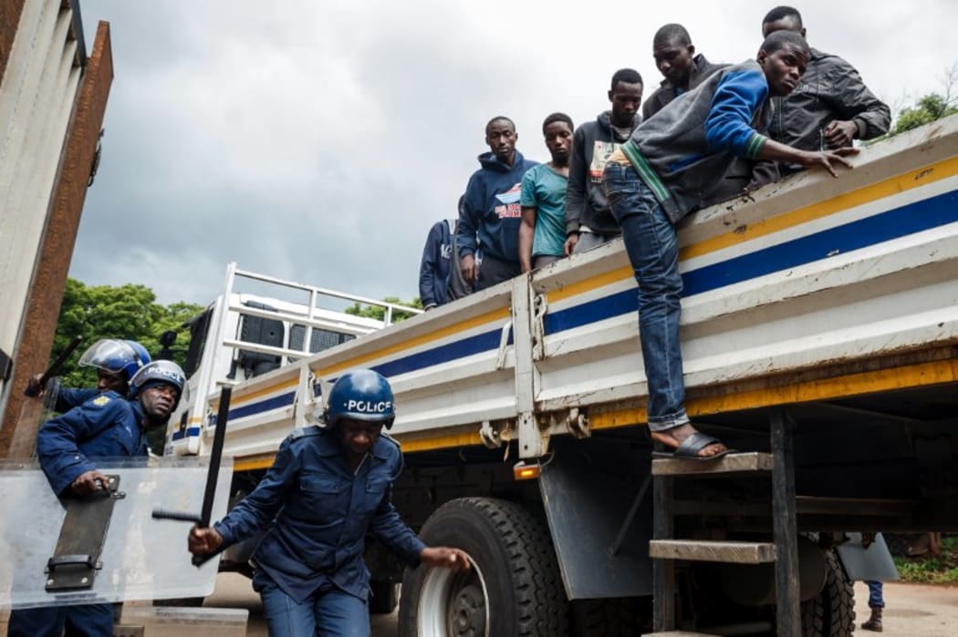 Zimbabwean anti-riot police forces watch men, arrested during violent protests triggered by a sudden rise in fuel prices announced by Zimbabwean President, for their hearing in Harare,