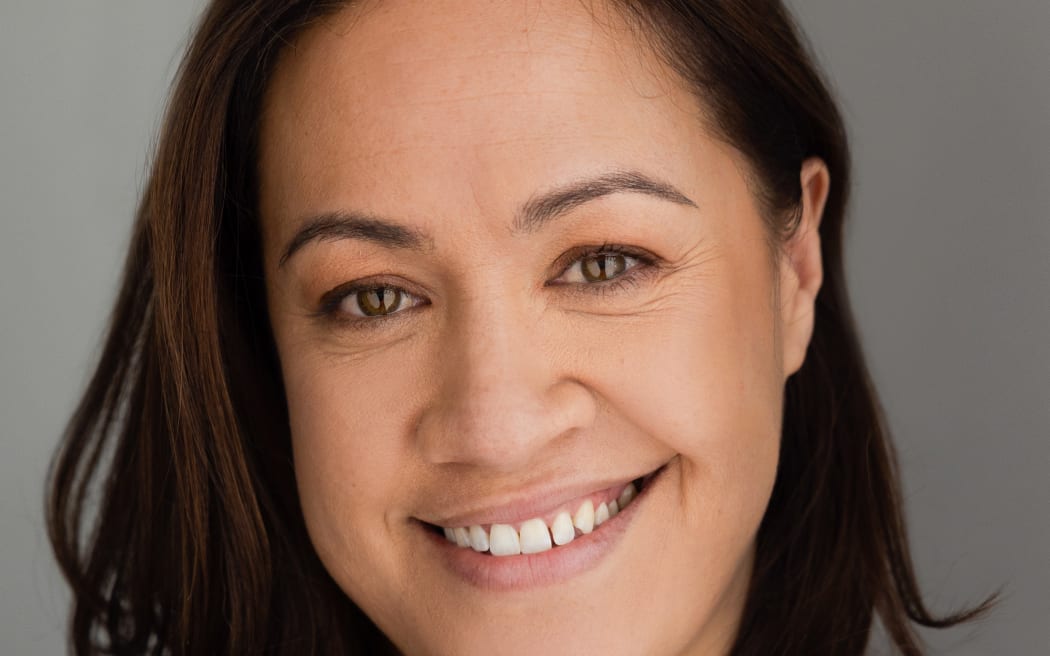 This is a headshot of Stacey Leilua. She is smiling with teeth showing. The background behind her is grey.