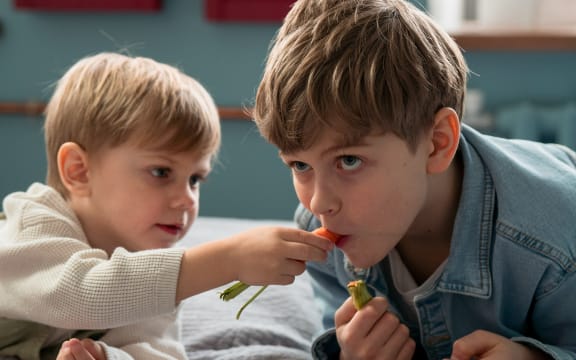Two boys sharing a carrot