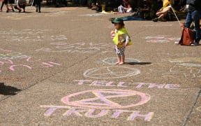 A child walks on slogans that Extinction Rebellion activists wrote in chalk at a gathering in Sydney.