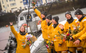 French skipper Alexia Barrier (L) and crew members Dee Caffari, Annemieke Bes, Tamara Echegoyen, Rebecca Gmuer Hornell, Deborah Blair, Molly Lapointe and Stacey Jackson celebrate with the public after mooring at the Brest harbour on the Ultim multihull Idec Sport and upon crossing the finish line of the Jules Verne Trophy, off the coast of Brest, Brittany, on January 26, 2026.