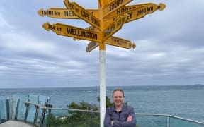 Journalist and author Naomi Arnold standing in front of the signposts at Bluff, the start of Te Araroa trail