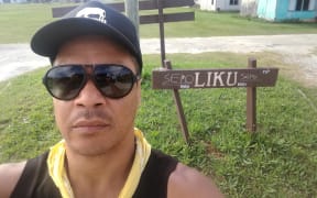 Actor Shimpal Lelisi poses before the sign identifying his village of Liku in Niue.