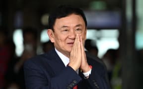 Former Thai Prime Minister Thaksin Shinawatra greets his supporters after landing at Bangkok's Don Mueang airport on August 22, 2023. Thaksin Shinawatra bowed in homage to the Thai king's portrait as he returned to the kingdom Tuesday after 15 years in exile, before being led away by officials to be processed on multiple outstanding criminal cases. (Photo by Manan VATSYAYANA / AFP)
