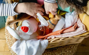 A woman rummages in a basket of cleaning products