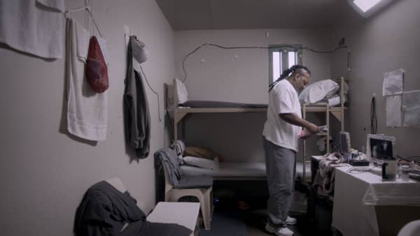 Missouri maximum security prisoner Chill, in Netflix documentary The Quilters, stands in his room holding some paper.