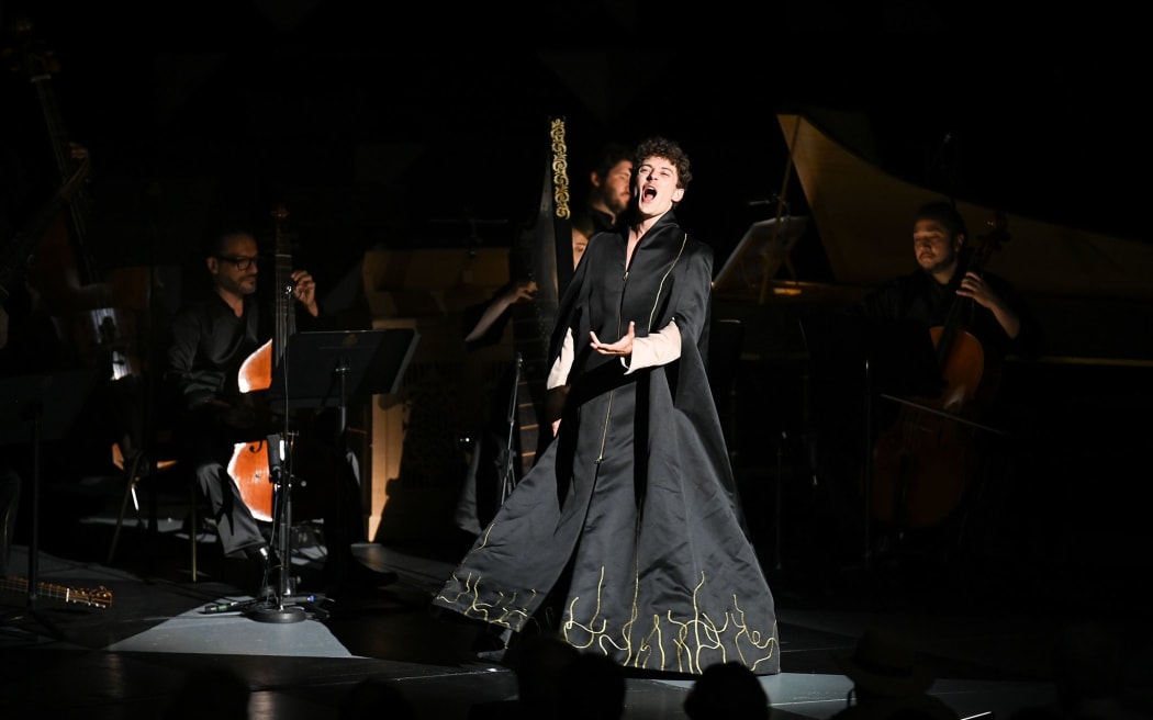 Counter-tenor Jakub Józef Orliński sings on stage wearing a dramatic black and gold coat.
