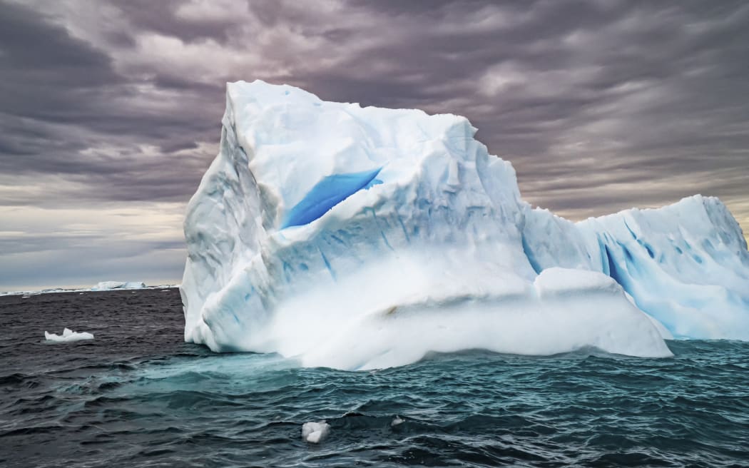 Melting iceberg with ice floe in foreground. Photographed off Antarctica. (Photo by PHOTOSTOCK-ISRAEL/SCIENCE PHOTO / PSI / Science Photo Library via AFP)