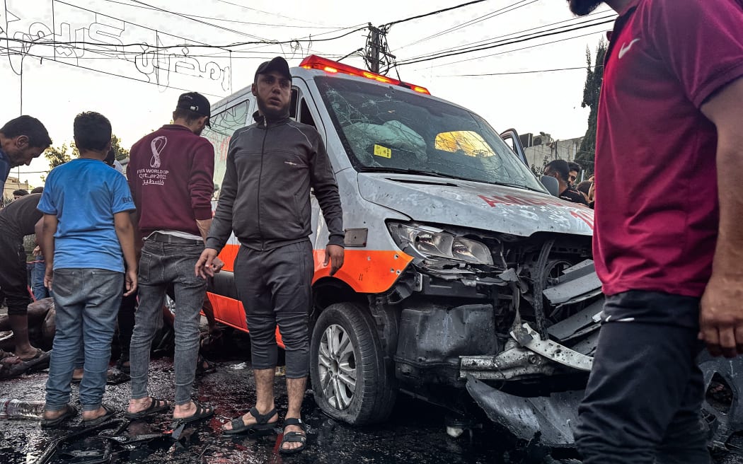 People gather around an ambulance damaged in a reported Israeli strike in front of Al-Shifa hospital in Gaza City on November 3, 2023, as battles between Israel and the Palestinian Hamas movement continue. According to the head of the Hamas government's press service, the strike targeted "an ambulance convoy which was preparing to transport wounded people from Al-Shifa hospital" to the border with Egypt. Several people were killed and injured in the strike. (Photo by MOMEN AL-HALABI / AFP)