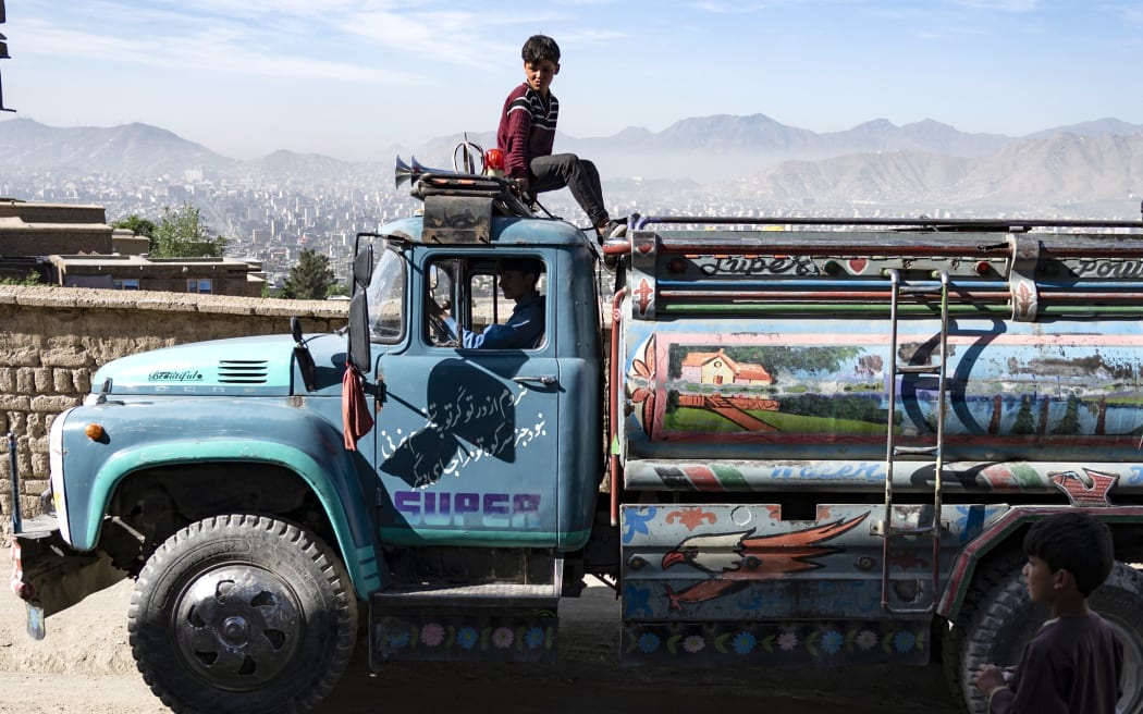 In this picture taken on April 27, 2025, an Afghan boy sits atop a potable water tanker on a hillside in Kabul. Kabulis will have to lug water in heavy jugs from wells or buy it from tankers -- which charge at least twice as much as the state-owned utility, with potable water even more pricy as the city struggles to combat an entrenched water crisis, in a country where 85 percent of the population lives on less than a dollar a day, according to the United Nations. (Photo by Wakil KOHSAR / AFP) / TO GO WITH: AFGHANISTAN-WATER-URBAN-PLANNING, REPORTAGE BY SUSANNAH WALDEN
