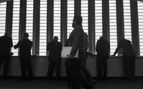 A silhouette of men in suits against a window at the United Nations in New York