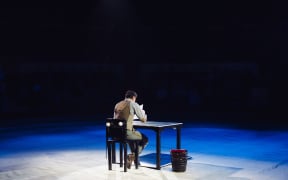 A lone office worker in a dark room.