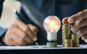 Business man holding light bulb on the desk in office and writing on note book it for financial, accounting, energy, idea concept, power, bill, money