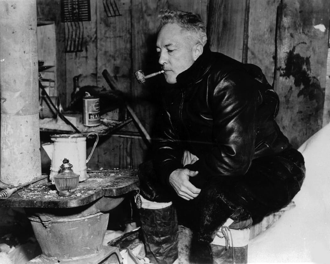 Rear Admiral Richard Byrd revisits his old hut at the site of Little America II. He is smoking 12-year old tobacco in a 12-year old corncob pipe left at the camp in 1935. This photo was taken in 1947 during the US Navy's Operation Highjump expedition.