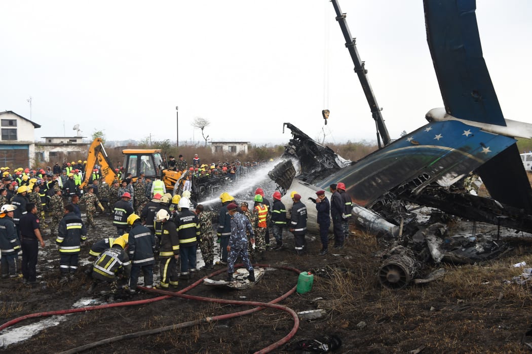 Nepali rescue workers gather around the debris from the deadly plane crash.