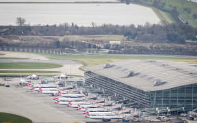An aerial photograph taken on March 21, 2025 shows planes parked on the tarmac of Heathrow Airport following its closure after a fire broke out at a substation supplying power of the airport, in Hayes, west London. Britain's Heathrow airport, Europe's busiest, was shut down early on March 21 for 24 hours after a major fire at an electricity substation cut power to the sprawling facility west of London, officials said. (Photo by AFP)