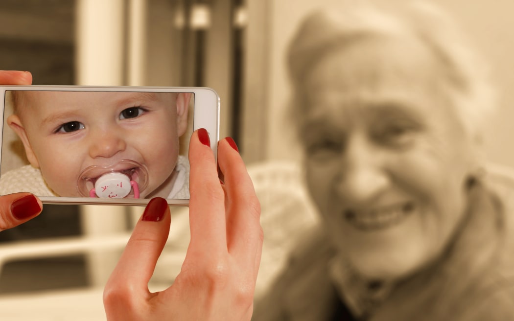 Photoshopped image of phone camera used on elderly woman, showing her image as a baby, to indicate ageing.